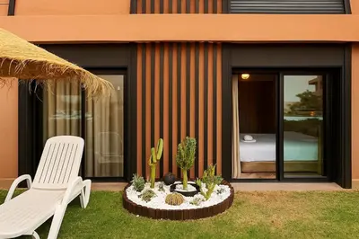a patio with a white chair and cactuses and a bedroom at Évasion à Marrakech confort, verdure et piscine in Marrakech