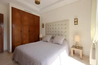 a bedroom with a white bed and a wooden door at Apartment in the Heart of Marrakech 5th Floor in Marrakech