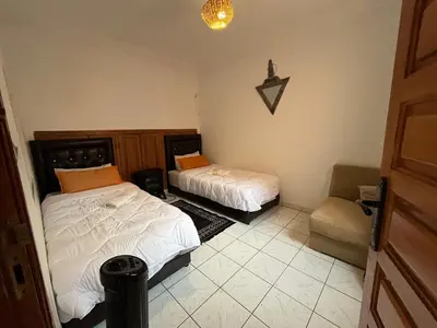 a bedroom with two beds and a chair in it at Riad Flouris in marrakech in Marrakech