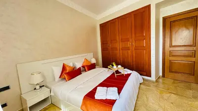 a bedroom with a large bed with red and white sheets at Heart of Marrakech Chic & Central Gueliz Apartment - Free parking in Marrakech