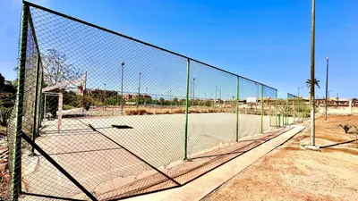 a chain link fence with a tennis court at Palmeraie 1BR Appart with Garden, Pools and Tennis in Marrakech