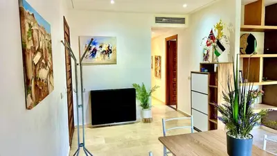 a living room with a table and a television in it at Palmeraie 1BR Appart with Garden, Pools and Tennis in Marrakech
