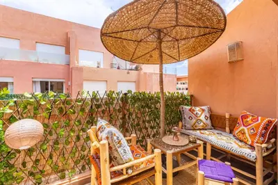 a patio with two chairs and an umbrella at Luxe et Élégance au cœur de Marrakech in Marrakech