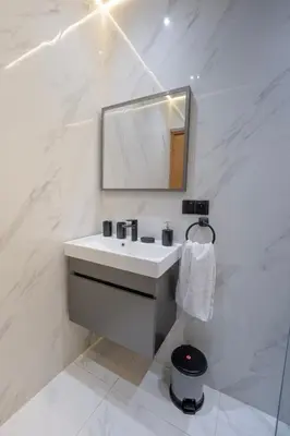a white bathroom with a sink and a mirror at Charming Central 2 Bedroom Apartment with Pool Near Train Station in Marrakech