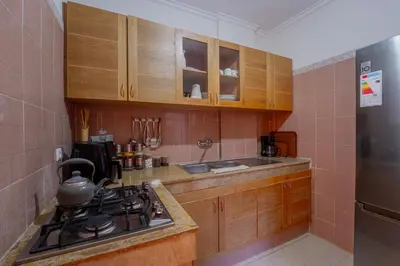 a kitchen with wooden cabinets and a stove top oven at Charming Central 2 Bedroom Apartment with Pool Near Train Station in Marrakech