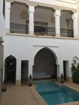 a villa with a swimming pool and a balcony at Oasis de la Médina -Piscine Chauffée - Climatisation Petit-Déjeuner et Gouvernante in Marrakech