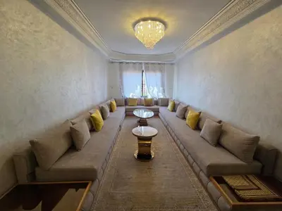a living room with a long couch and a chandelier at andlous 4 in Marrakech
