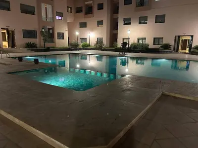 a swimming pool in a building with blue water at appartement vue piscine enjoy & relax in Marrakech