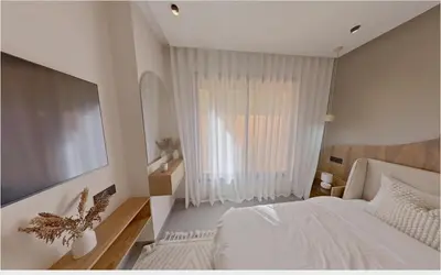 a bedroom with a white bed and a large window at Appartement chic Menara Mall piscine Rooftop in Marrakech