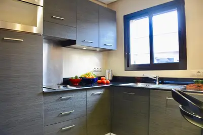 a kitchen with wooden cabinets and a sink and a window at 1 King BR with AC, Roof Pool & View-Perfect for 2- City Center in Marrakech