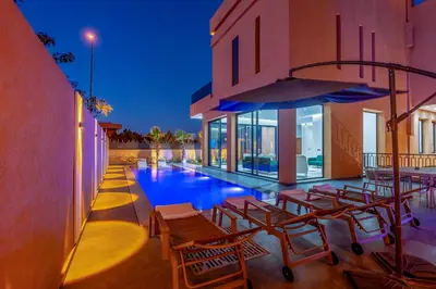 a swimming pool with a bunch of chairs next to a building at Villa Santa Marrakech in Marrakech