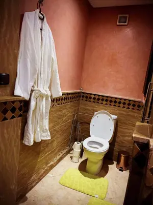 a bathroom with a toilet and a towel hanging on the wall at Guéliz Horizon - Central Apartment in Miramas2 in Marrakech