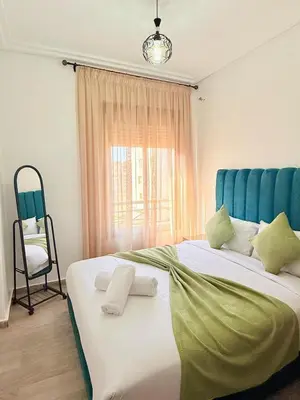a bedroom with a large bed with a blue headboard and a chair at A24 Confortable Moderne Au Centre-ville in Marrakech