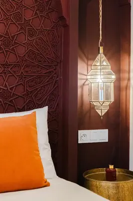 a bed with an orange pillow and a lamp at Riad Imrani - piscine - 6 mn from Jamaa Al Fna in Marrakech