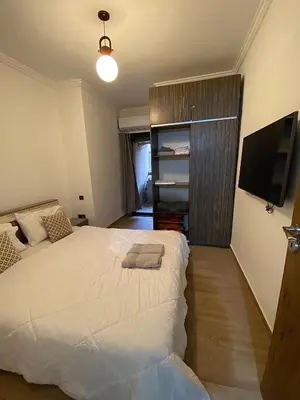 a bedroom with a large white bed and a television at Appartement 1 chambre à Gueliz Confort et piscine in Marrakech
