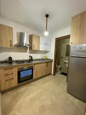 a kitchen with wooden cabinets and a stainless steel refrigerator at Appartement 1 chambre à Gueliz Confort et piscine in Marrakech