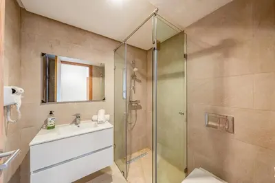a bathroom with a glass shower and a sink at Appartement moderne et spacieux avec terrasse et piscine au Noria Golf in Marrakech