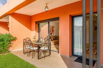 a dining room with a table and chairs on a patio at Appartement moderne et spacieux avec terrasse et piscine au Noria Golf in Marrakech