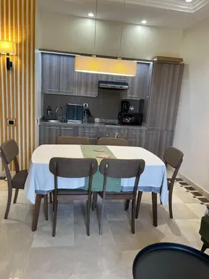 a dining room with a table and chairs and a kitchen at Appartement de charme au Vizir Resort in Dar Caïd Layadi