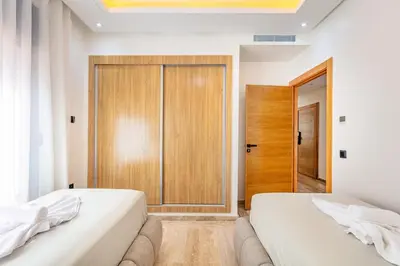 two beds in a room with a sliding door at Atlas Light Heart of Gueliz & Parking in Marrakech