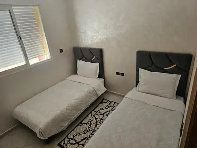 two beds in a small room with a window at View Marrakech Apartment in Marrakech