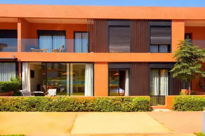 an orange building with glass windows and a patio at Ground floor 2 elegant bedrooms with direct pool access in Marrakech