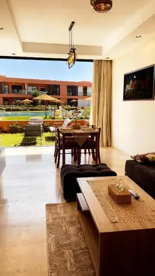 a living room with a table and a couch at Ground floor 2 elegant bedrooms with direct pool access in Marrakech