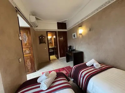 a hotel room with two beds and a hallway at Échappée onirique au cœur de la Cité Ocre in Marrakech