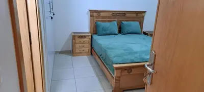 a bedroom with a wooden bed with blue pillows at Menara Amandier in Marrakech