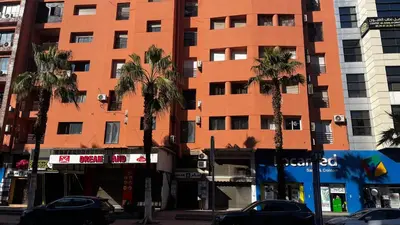 a tall orange building with palm trees in front of it at Dreams in Marrakech in Marrakech