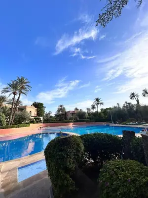 a large swimming pool with palm trees in the background at Condo in the Heart of the Palmeraie, Pools in Marrakech