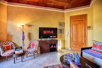 a living room with a tv and a couch and chairs at Condo in the Heart of the Palmeraie, Pools in Marrakech