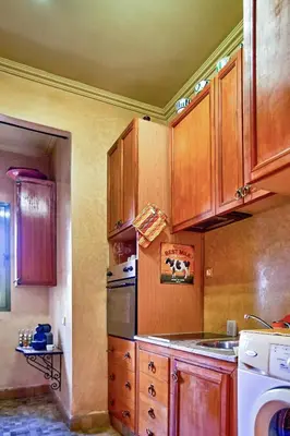 a kitchen with wooden cabinets and a stove top oven at Condo in the Heart of the Palmeraie, Pools in Marrakech