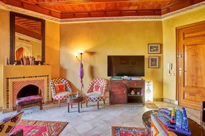 a living room with a fireplace and a tv at Condo in the Heart of the Palmeraie, Pools in Marrakech