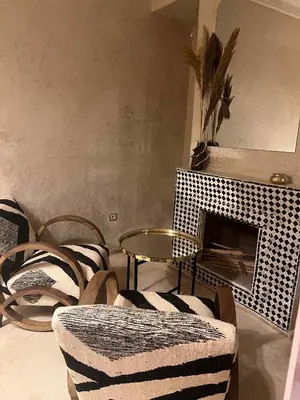 a living room with chairs and a table and a fireplace at Riad Paillettes in Marrakech