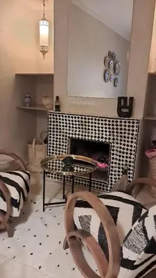 a living room with a table and a fireplace at Riad Paillettes in Marrakech