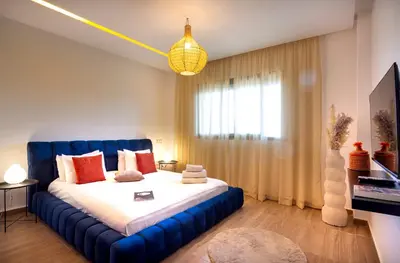 a bedroom with a blue bed and a window at Luxueux appartement piscine coralia in Marrakech