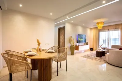 a living room with a table and chairs and a couch at Luxueux appartement piscine coralia in Marrakech