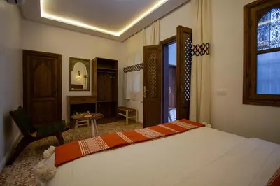 a bedroom with a bed and a chair and a window at Riad Jô & Spa in Marrakech