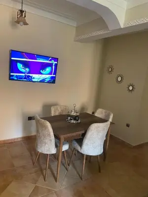 a dining room table with chairs and a tv on the wall at Bel appartement 1er étage aux portes de gueliz in Marrakech