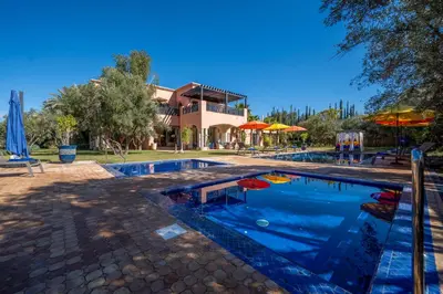 a swimming pool with a house in the background at Villa Juzyan Piscine-Jacuzzi-Pataugeoire-Pétanque in Marrakech