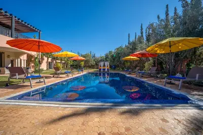 a swimming pool with umbrellas and tables and chairs at Villa Juzyan Piscine-Jacuzzi-Pataugeoire-Pétanque in Marrakech