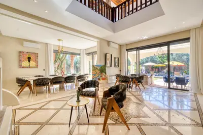 a living room with chairs and a dining room at Villa Juzyan Piscine-Jacuzzi-Pataugeoire-Pétanque in Marrakech