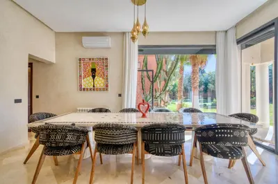 a dining room with a glass table and chairs at Villa Juzyan Piscine-Jacuzzi-Pataugeoire-Pétanque in Marrakech