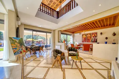 a living room with a table and chairs at Villa Juzyan Piscine-Jacuzzi-Pataugeoire-Pétanque in Marrakech