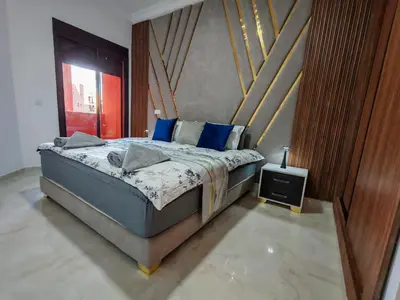a bedroom with a large bed with blue pillows at Elegant Apartment with King-Size Bed, Premium Amenities, 5 Pools & Free Parking in Marrakech