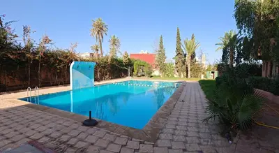 a swimming pool with blue water in a yard at Elegant Apartment with King-Size Bed, Premium Amenities, 5 Pools & Free Parking in Marrakech