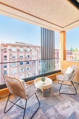 a balcony with chairs and a table and a large window at Modern Jewel Central and Premium comfort in Marrakech