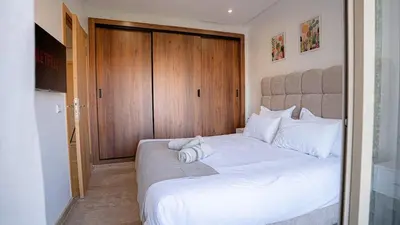 a bedroom with a large white bed with a wooden door at Stylish Gueliz Getaway, Terrace & Parking in Marrakech