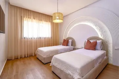 two beds in a room with an arched window at New Charming apartment with swimming pool in Marrakech